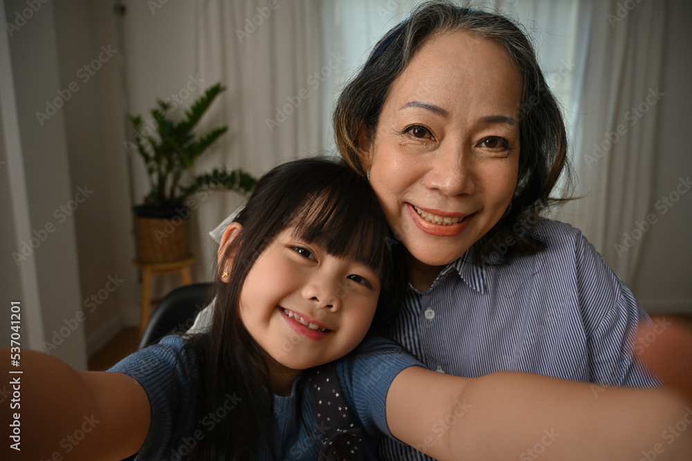 Old grandma and her little preschool granddaughter holding cellular taking self-portrait picture. Old grandma and her little preschool granddaughter holding cellular taking self-portrait picture.