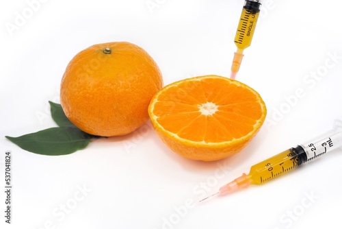 Close up syringe needle put on cut orange leaf on white background, concept cosmetic, fruit, vitamin C, natural, organic, beauty, treatment, intravenous 