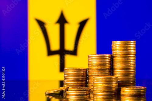 A stack of gold coins on the background of the flag of Barbados. Country economy concept