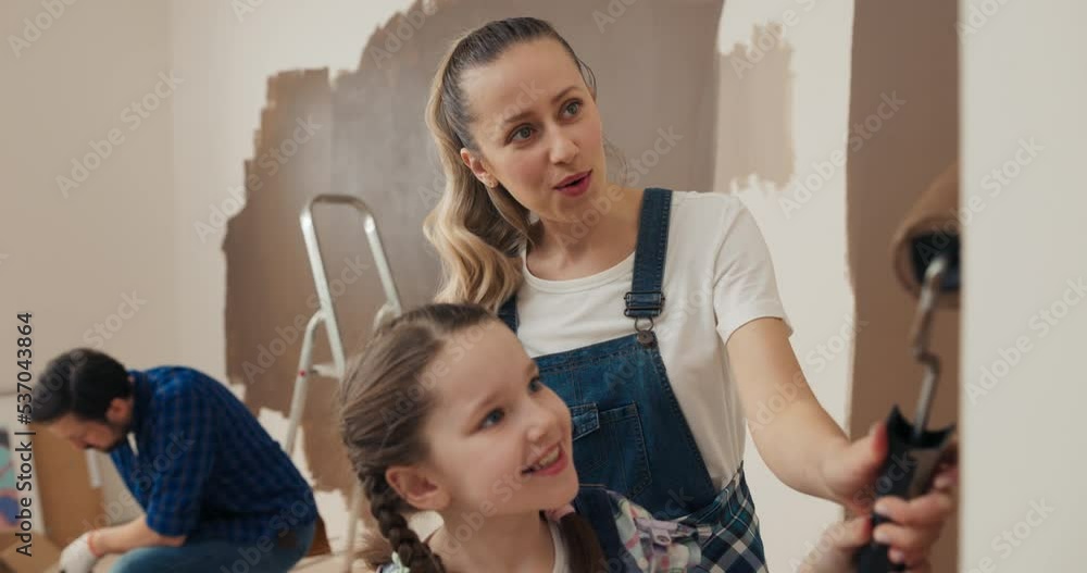 Family is renovating house and painting walls. Mother with curly hair