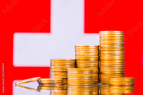 A stack of gold coins on the background of the flag of 
Switzerland. Country economy concept photo