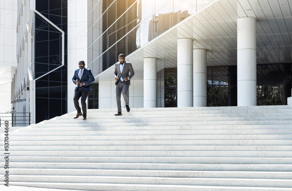 Business people walk down the stairs to a modern glass building. Work in a large company. Career growth and advancement. Increasing and improving skills. Salary increase Business people walk down the stairs to a modern glass building. Work in a large company. Career growth and advancement. Increasing and improving skills. Salary increase