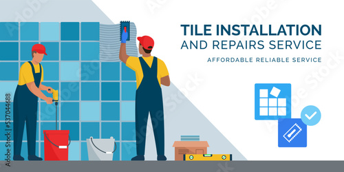 Professional tilers installing tiles on a wall