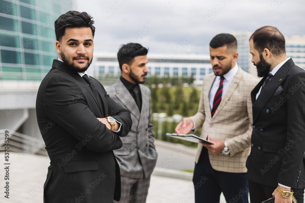 Business people outdoor meeting. Portrait of a business man against the background of a group of people and buildings of the city center Business people outdoor meeting. Portrait of a business man against the background of a group of people and buildings of the city center