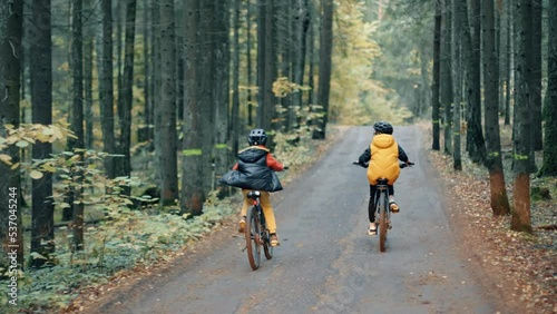 Two kids riding on mountains bike in the forest. Boys in helmets cycling on the autumn nature trail. Active smiling children on bikes.