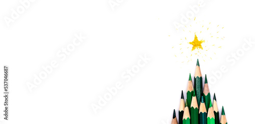 A creative Christmas tree made of green pencils on a white background, a yellow star made of shavings on the top.Christmas and New Year flat lay.