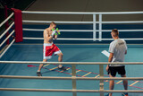 Two sportive men, professional boxer and personal trainer is practicing boxing at gym. Sport, strength, energy and power