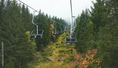 Chairlift in a forest on a foggy day, color toning applied.