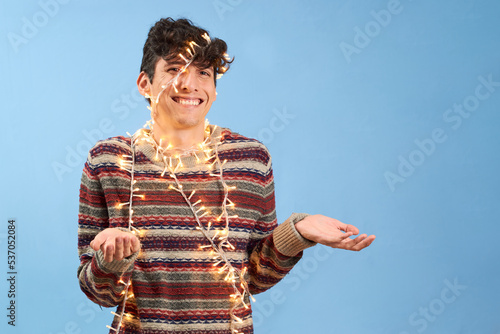 Happy young man entangled in christmas lights, isolated. photo