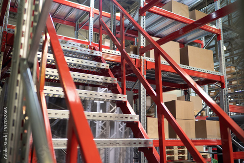 industrial mezzanine. Multi-tier shelving systems. Industrial mezzanine inside building. Steel warehouse furniture with cardboard boxes. Staircase at mezzanine. Semi-permanent production structures