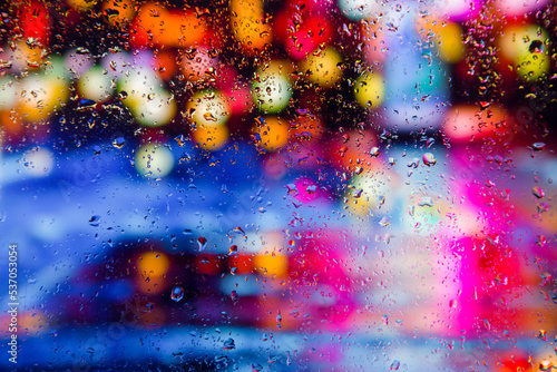 City view through a window on a rainy night Rain drops on window with road light bokeh  City life in night in rainy season abstract background. Focus on drops on glass