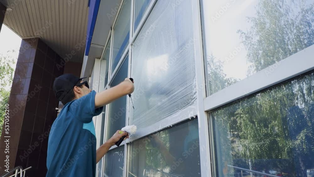 Close-up video of a cleaning service specialist washes and cleans the windows and facade of the building Close-up video of a cleaning service specialist washes and cleans the windows and facade of the building