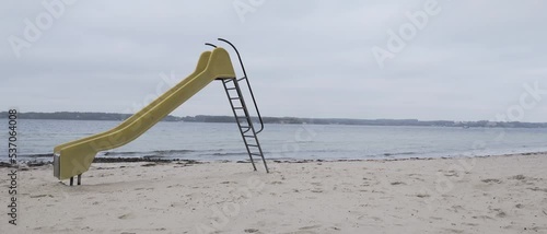 Lonely yellow slide at a beach in extra wide format with low contrast