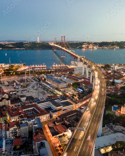 Aerial view of April 25th bridge with Christ the King statue (Cristo Rei) in background at sunset, view of Lisbon skyline at night, Alcântara, Lisbon, Portugal. photo