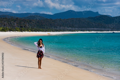 Photo beautiful girl in dress and shirt and hat walks on paradise beach with white san