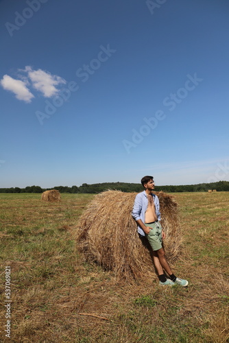 guy resting in a field on a haystack