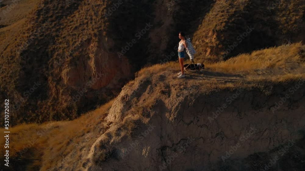happy woman brunette with blowing hair stands on hill top with panoramic view at sunset with welsh corgi dog. beautiful girl enjoying adventure in nature. Stanislav canyon, Kherson region, Ukraine happy woman brunette with blowing hair stands on hill top with panoramic view at sunset with welsh corgi dog. beautiful girl enjoying adventure in nature. Stanislav canyon, Kherson region, Ukraine