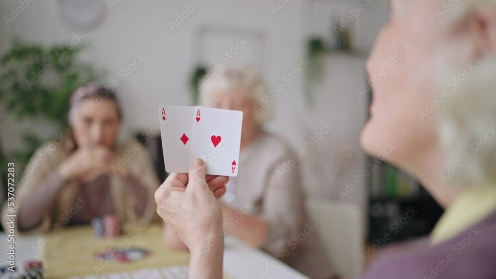 Senior woman showing pair of aces, winning game, grandmas playing poker at home Senior woman showing pair of aces, winning game, grandmas playing poker at home