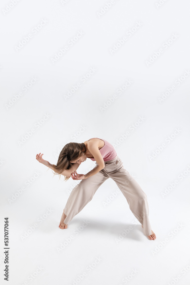 Young beautiful slim girl dances contemporary on a beige studio background Young beautiful slim girl dances contemporary on a beige studio background