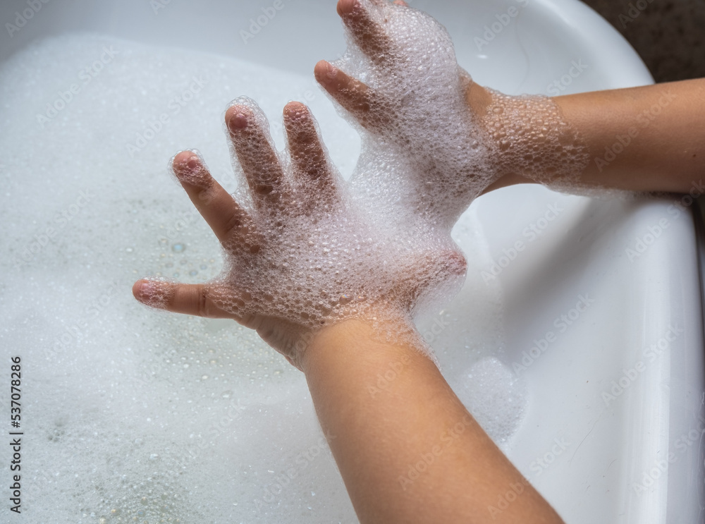 Fototapeta premium Child washing hand full of foam in bathroom sink