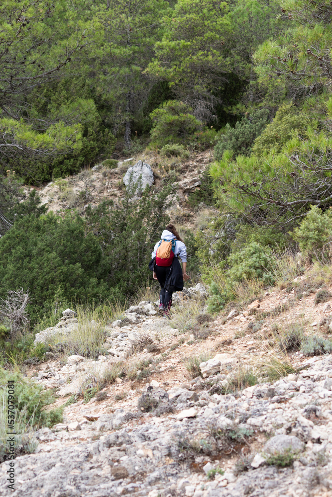 Mujer caminando por una ruta a través de la montaña Mujer caminando por una ruta a través de la montaña