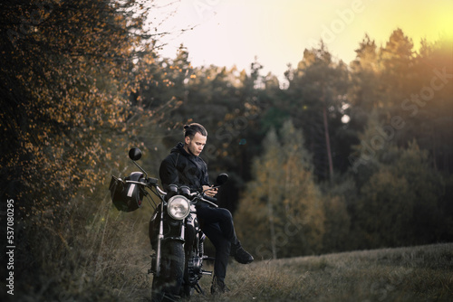 male biker motorcyclist with retro motorcycle in autumn forest. © velimir