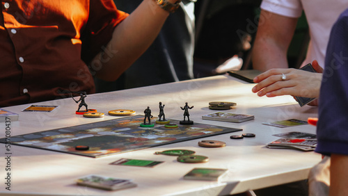 The concept of a board game and leisure. Adults, teenagers or children play board games. Hands with playing cards, chips and placed figures of characters on the table