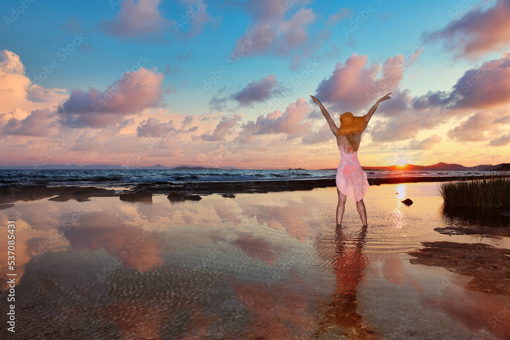 A young woman standing on the beach at the sunset