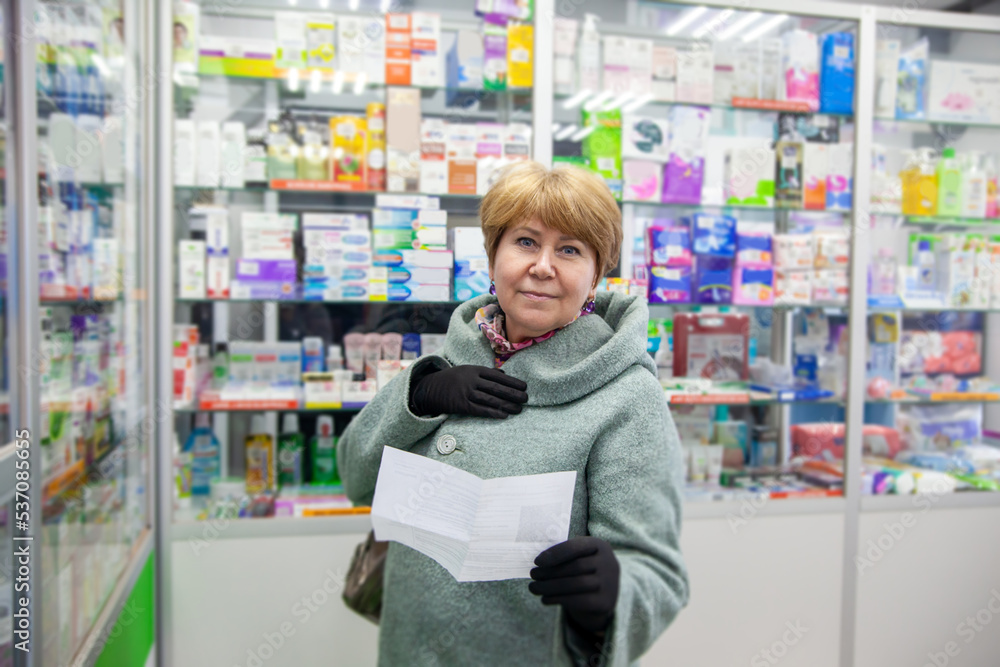 Elderly woman in   coat buys medicines at   pharmacy