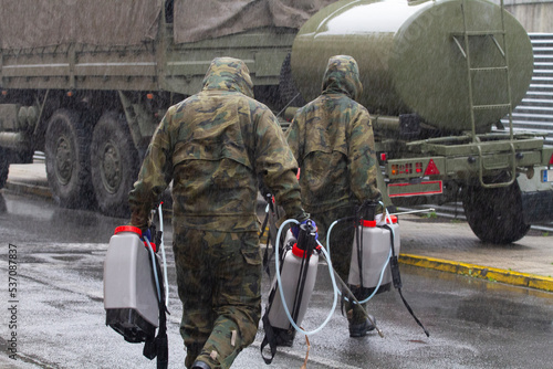 Two soldiers of the Spanish army carry sprayers and material to disinfect photo