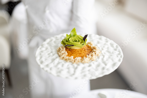 Slika na platnu Chef holds a plate with delicious vegetarian meal decorated with flower made of
