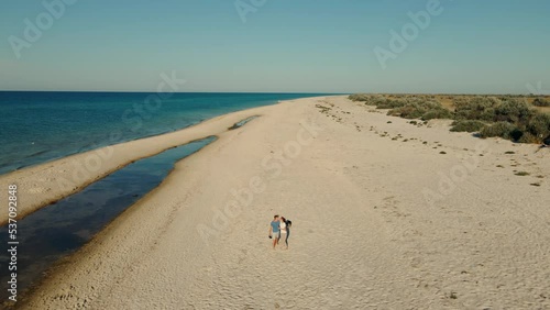 Wallpaper Mural Aerial footage from drone of Happy carefree couple with dog welsh corgi walks along sandy beach on shore of deserted island. happy man and woman hugging and kissing while summer vacation at seaside Torontodigital.ca