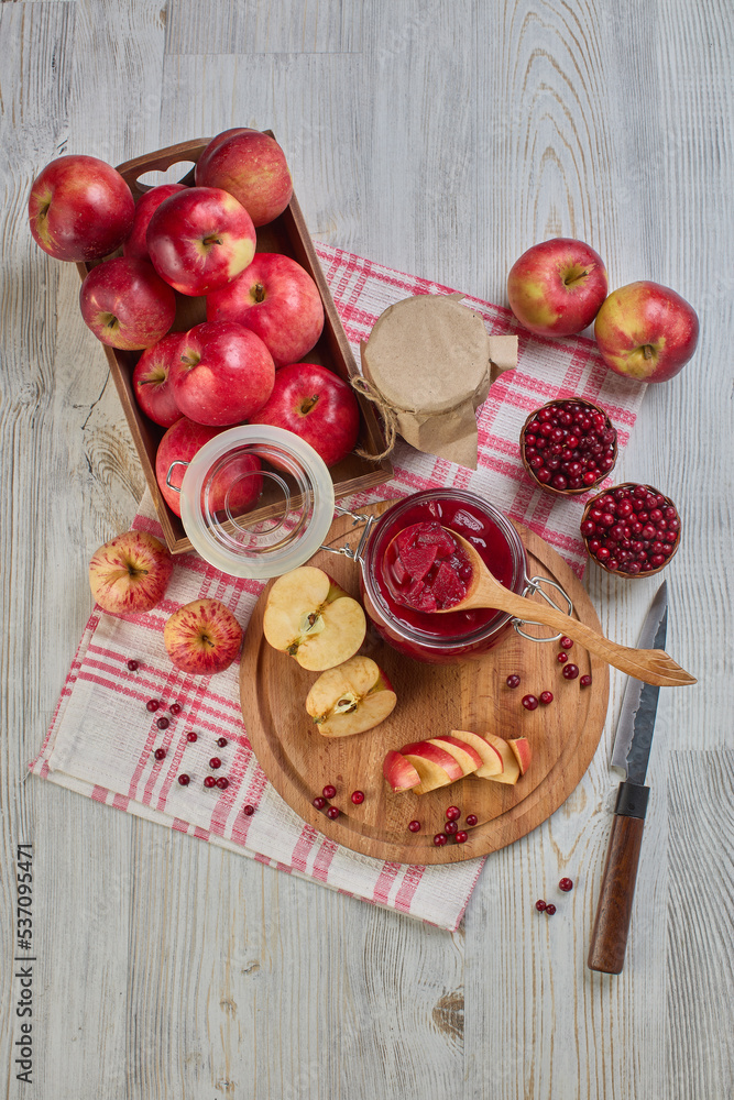 Wooden spoon with appetizing lingonberry and apple jam, jar of jam, fresh fruits and berries on light wooden table. Home canning Wooden spoon with appetizing lingonberry and apple jam, jar of jam, fresh fruits and berries on light wooden table. Home canning