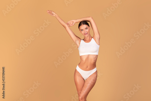 Depilation concept. Happy caucasian fit woman showing her smooth armpits, standing with hands up © Prostock-studio