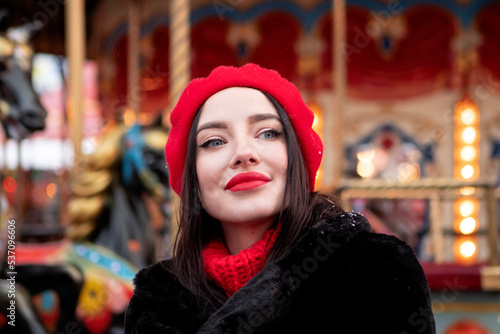 beautiful girl in a red beret and mittens in winter on New Year's street.