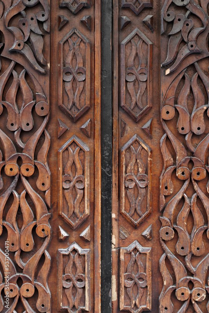 Texture in relief in a Parisian wooden door. The wood is damaged by time and use. The elements of the texture are rounded