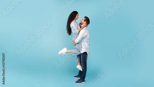 Cheerful millennial caucasian male raise arabic woman, have fun, enjoy tender moment at spare time