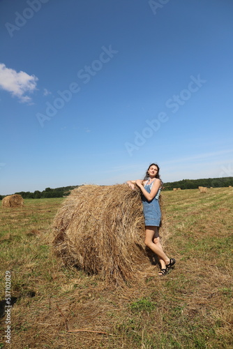 girl resting in a field on a haystack