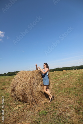 girl resting in a field on a haystack