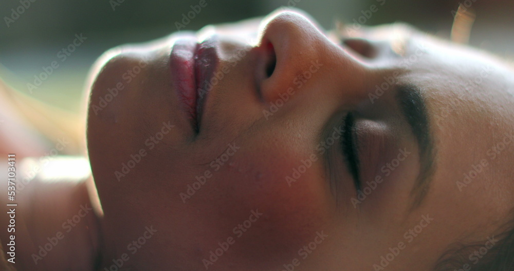 Fototapeta premium Woman opening eyes lied on grass outside daydreaming, relaxed girl