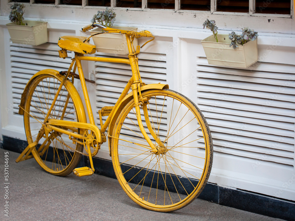 Yellow bicycle resting on white wall