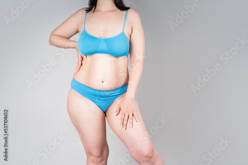 Fat woman in blue underwear on gray background, overweight female body