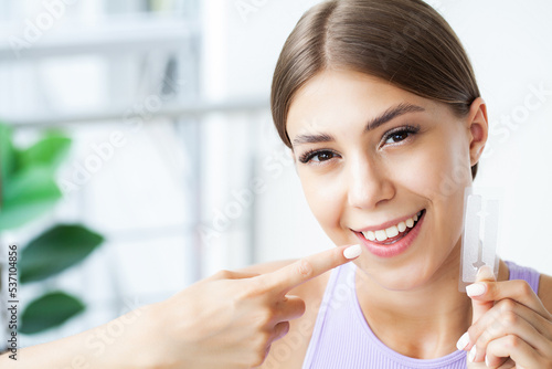 Teeth whitening  beautiful smiling woman holding a whitening strip.