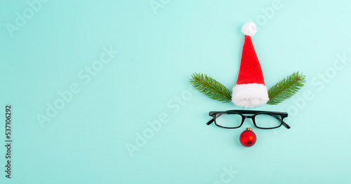 Konstfotografi Face of a reindeer with a red bauble nose, fir antlers, a santa claus hat and ey