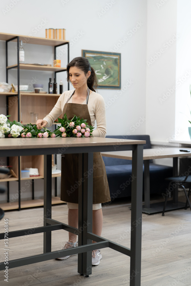 Florist woman working with flowers making a composition in her workshop