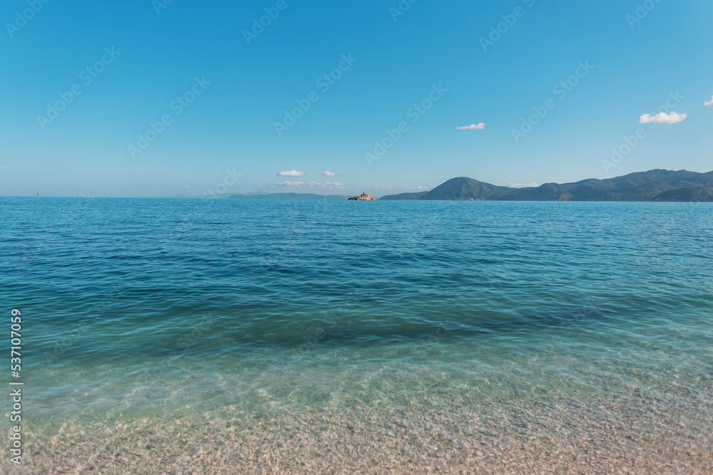 Beautiful blue clear sea with horizon, clear sky and mountains on the island of Elba, Italy. Summer travel and relaxing by the water