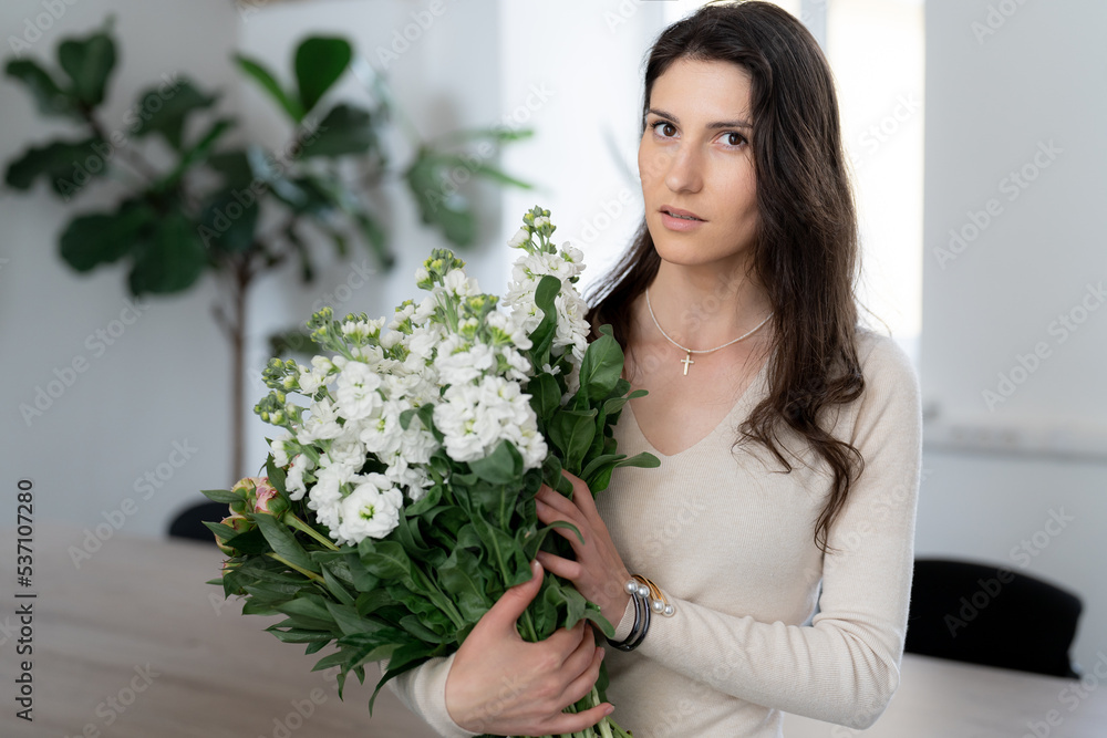 Positive woman holding a huge bouquet of flowers in her office. Birthday present smile. Positive woman holding a huge bouquet of flowers in her office. Birthday present smile.
