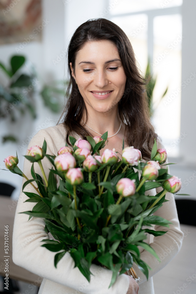Positive woman holding a huge bouquet of flowers in her office. Birthday present smile. Positive woman holding a huge bouquet of flowers in her office. Birthday present smile.
