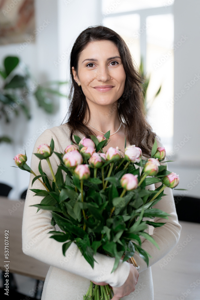 Positive woman holding a huge bouquet of flowers in her office. Birthday present smile. Positive woman holding a huge bouquet of flowers in her office. Birthday present smile.