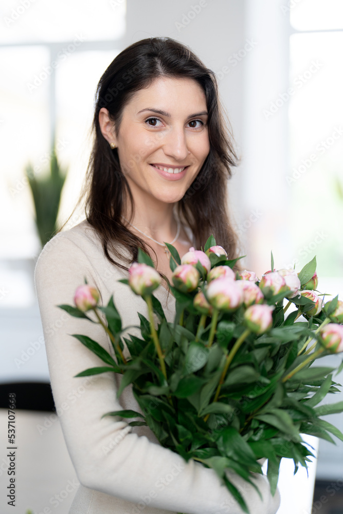 Positive woman holding a huge bouquet of flowers in her office. Birthday present smile. Positive woman holding a huge bouquet of flowers in her office. Birthday present smile.